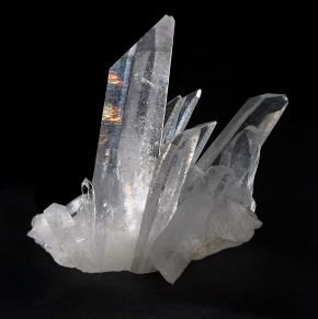A cluster of clear quartz crystals photographed against a black background