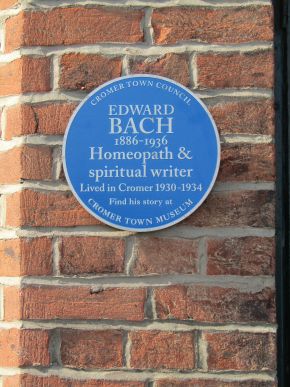 A round blue commemorative plaque for Edward Bach on a red brick wall