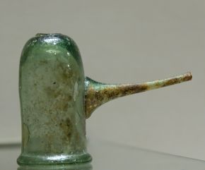 A small greenish blown-glass cup with a long thin spout on one side